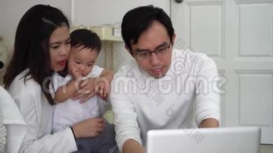 亚洲父亲和妻子一起用笔记本电脑工作，还有一个可爱的亚洲小男孩坐在家里舒适的房间里
